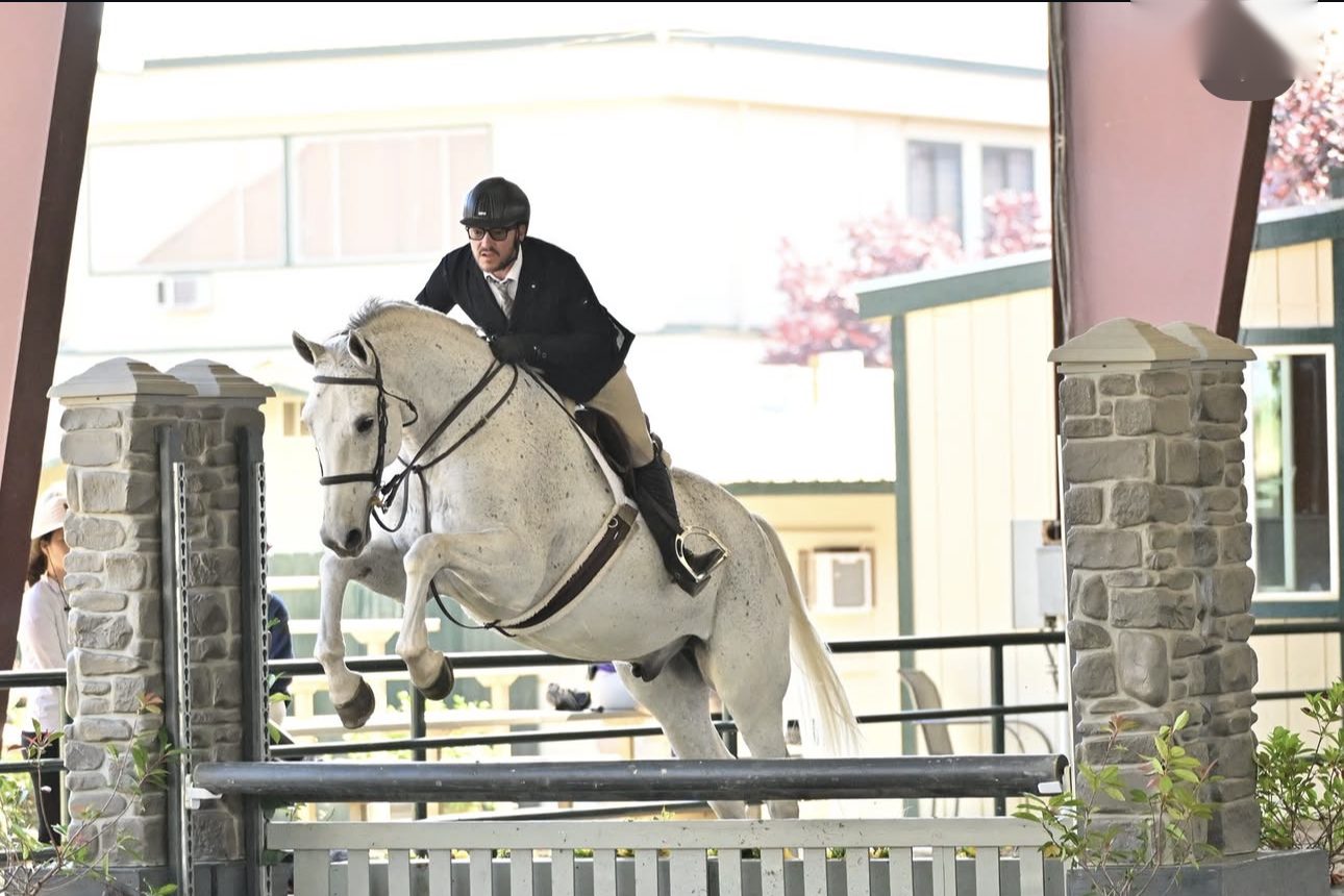 Ryan Oropeza on Rendezvous, hunter form over fence with stone pillars